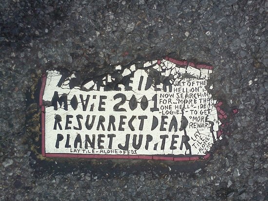 Decaying Toynbee Tile at corner of Eutaw and W. Franklin Street, across from H&H Building.